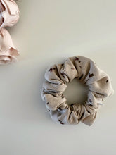 Load image into Gallery viewer, Baby scrunchie featuring a floral print on a ribbed beige fabric.