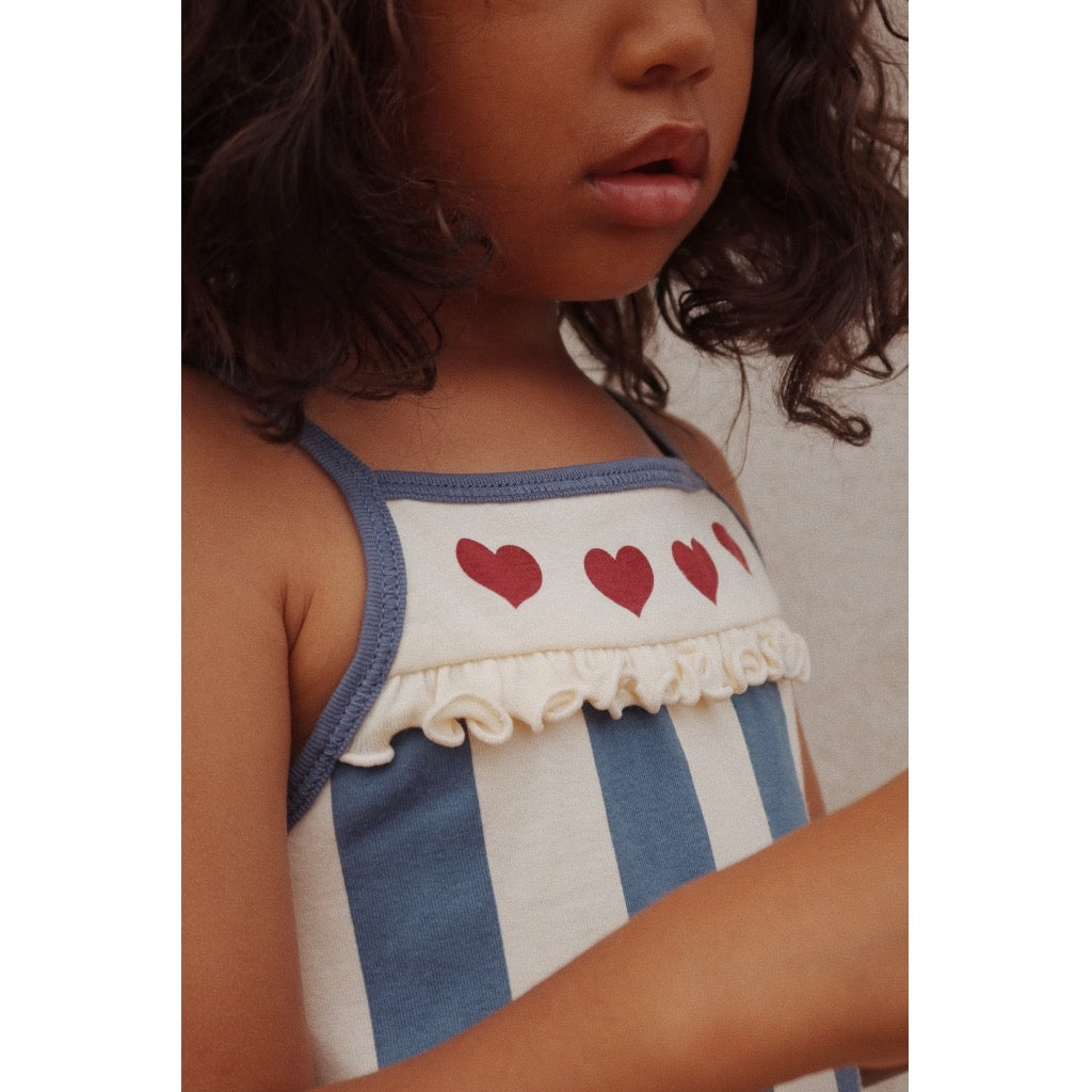 Organic cotton dress featuring a blue and white striped pattern with red hearts across the neckline. 