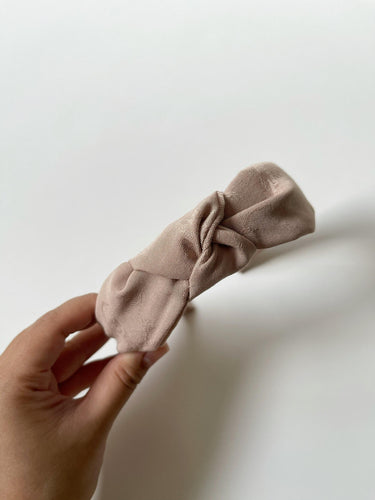 Beige structured headband featuring a floral pattern and knot at the top.