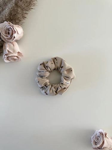 Baby scrunchie featuring a floral print on a ribbed beige fabric.