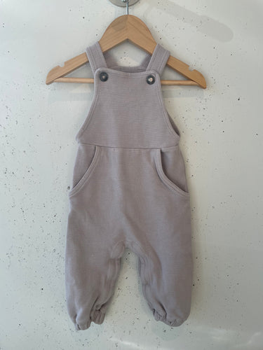 Lilac coloured comfy overalls featuring two snap buttons on straps and pockets on the front. 