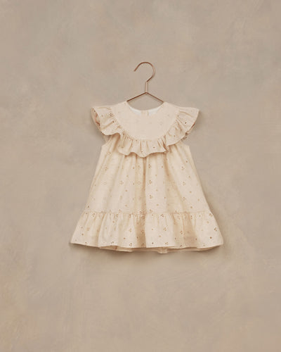 A-line neckline featuring a scoop ruffle and a ruffle at the bottom. The dress is featured in a pale yellow. 