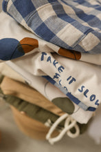 Load image into Gallery viewer, organic cotton white t-shirt with the words &quot;take it slow flow&quot; on the top left corner.
