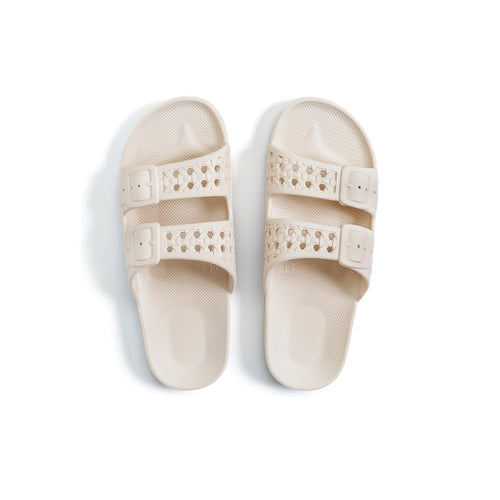 Women's cream two-strap slides with fixed buckles.