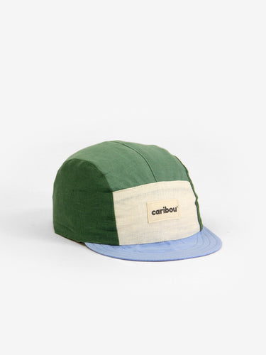 Baby cap featuring a five panel colour-block design. The colour block design features a light green, dark green, baby blue, and cream. 
