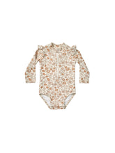 Load image into Gallery viewer, Beige coloured baby one piece rash guard with zipper on the front and ruffles on the shoulders. This rash-guard is featuring a floral print.
