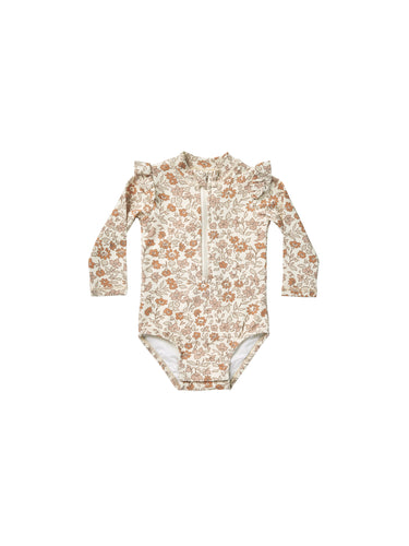 Beige coloured baby one piece rash guard with zipper on the front and ruffles on the shoulders. This rash-guard is featuring a floral print.