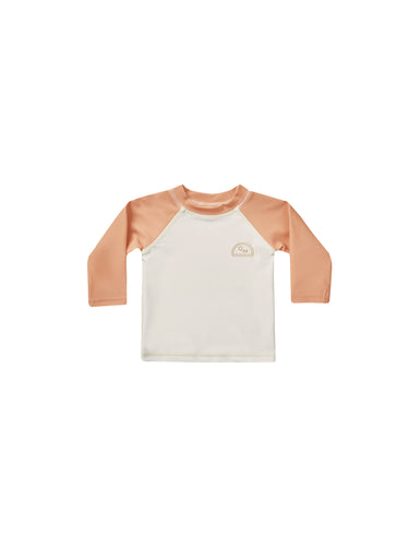 Beige baby rash-guard shirt with orange sleeves. 