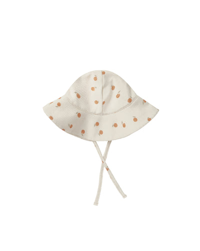 Beige baby sun hat featuring an orange all over print. 