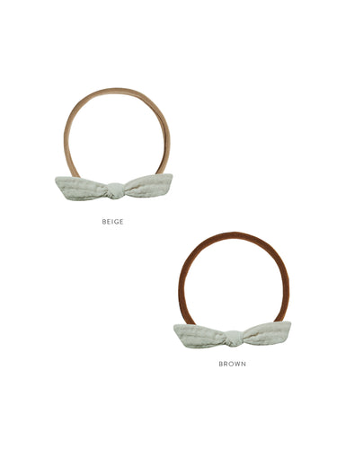 Little knot headband featuring a bow in a pale teal colour on a beige band. 