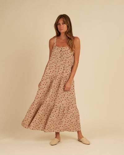 Beige linen maxi dress featuring a tiered skirt and red flowers all over. 