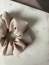 Load image into Gallery viewer, Baby scrunchie on a beige fabric.
